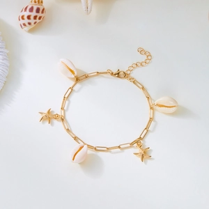 Close-up of gold paperclip chain anklet with starfish pendants and natural seashells