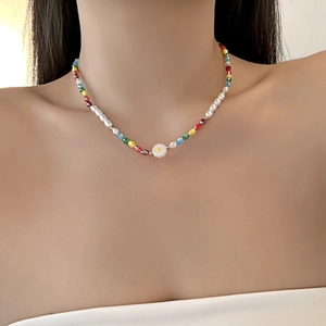 Detail of colorful beaded necklace with white flower pendant on female model neckline