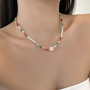 Detail of colorful beaded necklace with white irregular pearls and a small flower pendant