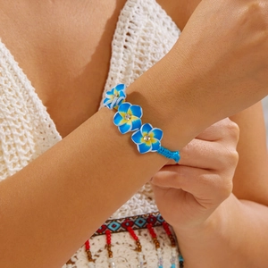 Detail eines handgewebten blauen Armbands mit drei blau-gelben Frangipani-Blüten