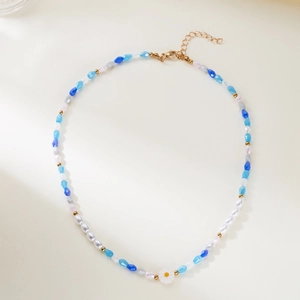 Detail of beaded necklace featuring blue resin pearls and a white daisy floral pendant