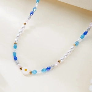 Detailed view of handmade beaded necklace with blue rhinestones and white daisy floral bead