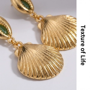 Detalle macro de pendientes de concha dorados con acabado texturizado y gema verde