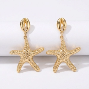 Detalle de pendientes de estrella de mar dorada con tachuelas de concha en soporte