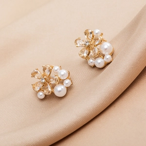 Gros plan de boucles d'oreilles fleurs dorées avec cristaux et perles élégantes