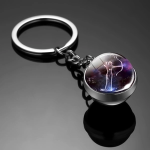 Macro detail of Sagittarius zodiac glass ball keychain with purple nebula galaxy pattern