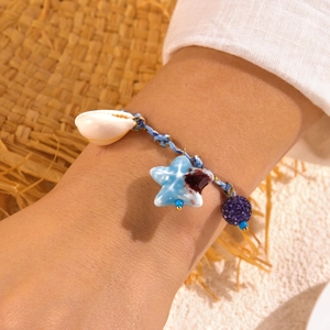 Detailed close-up of woven blue cord bracelet with shell and starfish charms