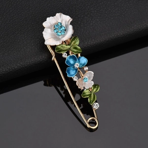 Blumennadel-Brosche mit blauen Strasssteinen und weißem Emaille auf goldenem Metallsockel