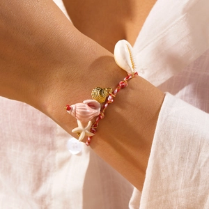 Detail of colorful woven cord bracelet with shell and starfish charms on a model wrist