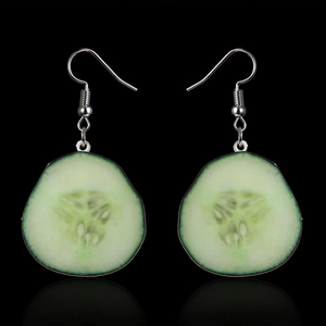 Macro detail of realistic green cucumber slice earrings with silver metal hooks on black background