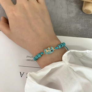Dettaglio del bracciale con perline turchesi e ciondolo a forma di elefante dorato