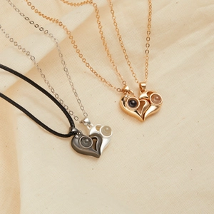 Detail of heart puzzle projection necklaces in gold and silver on white fabric