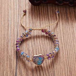 Detailed view of handmade woven heart stone bracelet with natural chakra beads on wood