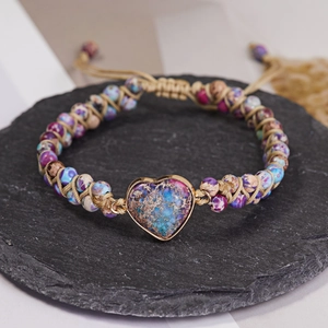 Macro detail of hand-woven bracelet featuring a heart-shaped stone and colorful beads