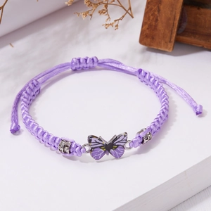 Dettaglio di bracciale viola intrecciato con farfalla, perline di cristallo e cordino