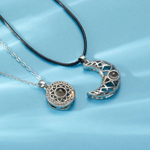 Detail of sun and moon magnetic couple necklaces with projection stone on blue background