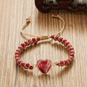 Close-up of handmade red marble stone heart pendant bracelet with adjustable woven strap