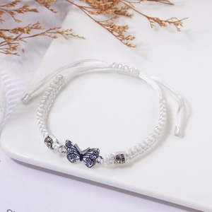 Dettaglio di un bracciale a farfalla bianco intrecciato a mano con perline e nodo regolabile
