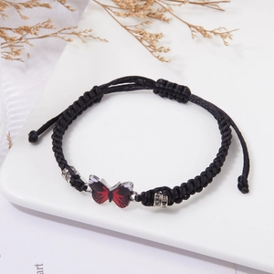 Dettaglio macro del bracciale intrecciato nero con farfalla rossa e strass luminosi