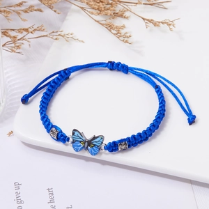 Dettaglio del braccialetto blu intrecciato a mano con ciondolo a farfalla e strass eleganti