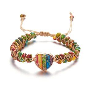 Detalle de pulsera artesanal con dije de corazón, cuentas de colores y cuerda boho