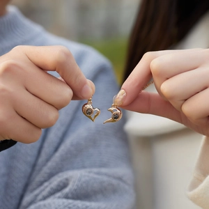 Detail of rose gold sun and moon magnet heart necklaces for couples with projection stone