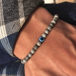 Macro detail of natural grey marble stone beads and blue evil eye charm on wrist