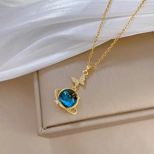 Detail of gold necklace with a sparkling butterfly and blue starry planet pendant
