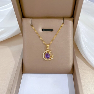 Macro detail of star and moon necklace with purple pear-cut stone on satin gift box