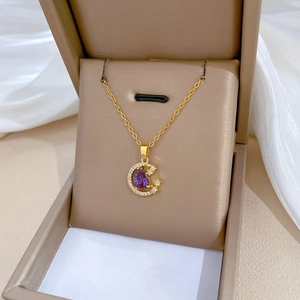Detailed macro of golden crescent moon pendant with purple gemstone and zircon in jewelry box