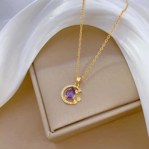 Detailed shot of golden crescent moon pendant with purple teardrop stone and tiny crystals