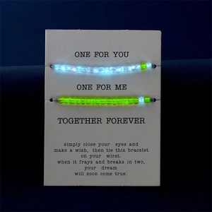 Braccialetti di coppia con perline luminose e fluorescenti su un biglietto d'auguri