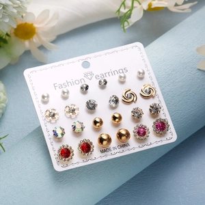 Detail view of 12-pair gold earring set with pearls and crystals on a white card
