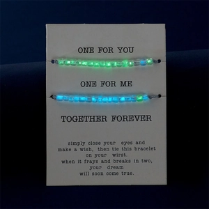 Dettaglio di due braccialetti con perline luminose su carta regalo con sfondo scuro
