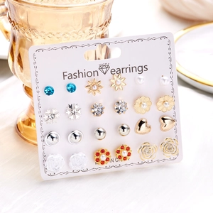 Detail view of 12 pairs of stud earrings featuring pearls and rhinestones on card