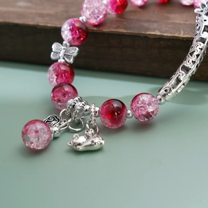 Macro shot of lily of the valley beaded bracelet with red floral beads and a cute cat charm