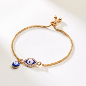 Detailansicht eines goldenen Evil Eye Armbands mit blauen Strasssteinen und verstellbarer Boxkette