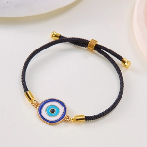 Detail eines verstellbaren schwarzen Webarmbands mit blauem Evil Eye und Goldakzenten