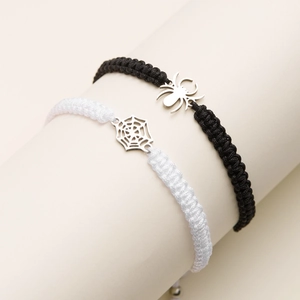 Détail de bracelets Halloween tissés main avec breloques araignée et toile sur support blanc