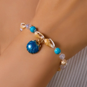 Detail of beach shell bracelet with turquoise beads and blue conch pendant on wrist