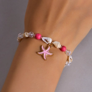 Close-up of summer shell beaded bracelet with pink starfish pendant on female wrist