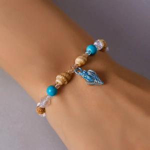 Detail of beach shell bracelet with blue metal pendant and beads on female wrist
