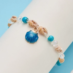Detailed close-up of beach seashell and blue bead bracelet on a display cylinder
