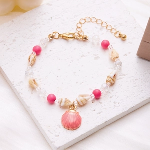 Detail of beach shell bracelet with pink scallop charm and small conch on white stone