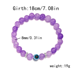 Dettaglio del bracciale di perle viola da 8mm con Evil Eye blu e distanziatori argentati