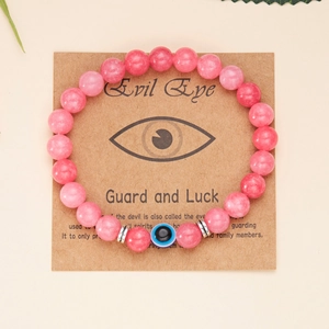 Dettaglio del bracciale Evil Eye con perline rosa su cartoncino kraft marrone di carta