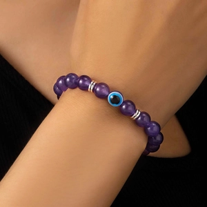 Dettaglio del bracciale con perle viola e ciondolo Malocchio al polso della modella