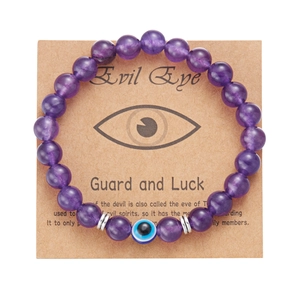 Dettaglio macro del braccialetto di perle viola 8mm con malocchio su carta regalo