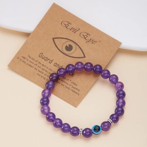 Dettaglio del bracciale viola con occhio greco esposto su un biglietto regalo kraft