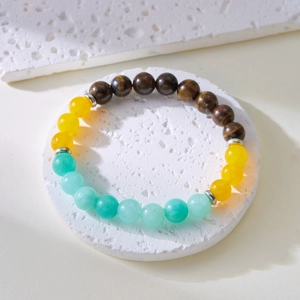 Top view of multi-color natural stone bracelet with tiger eye beads on white stone podium